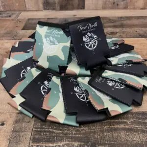 Stack of camouflage-patterned koozies with a logo and text.