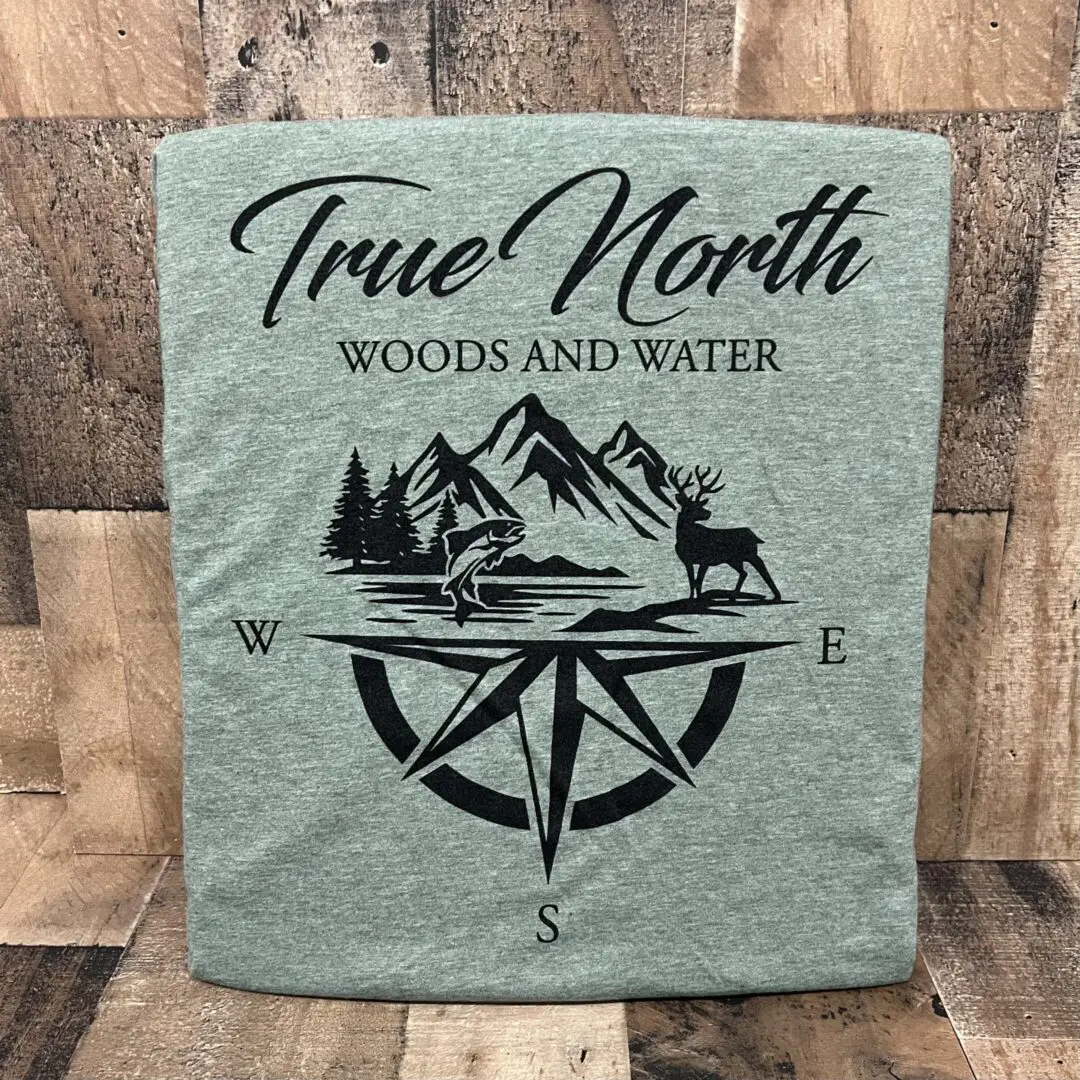 Green towel with a compass and nature design labeled 'True North Woods and Water'.