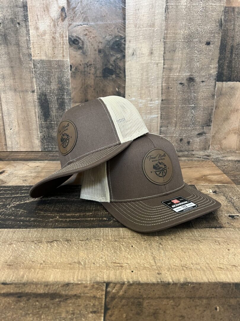 Two brown and beige trucker caps with a circular patch on the front.