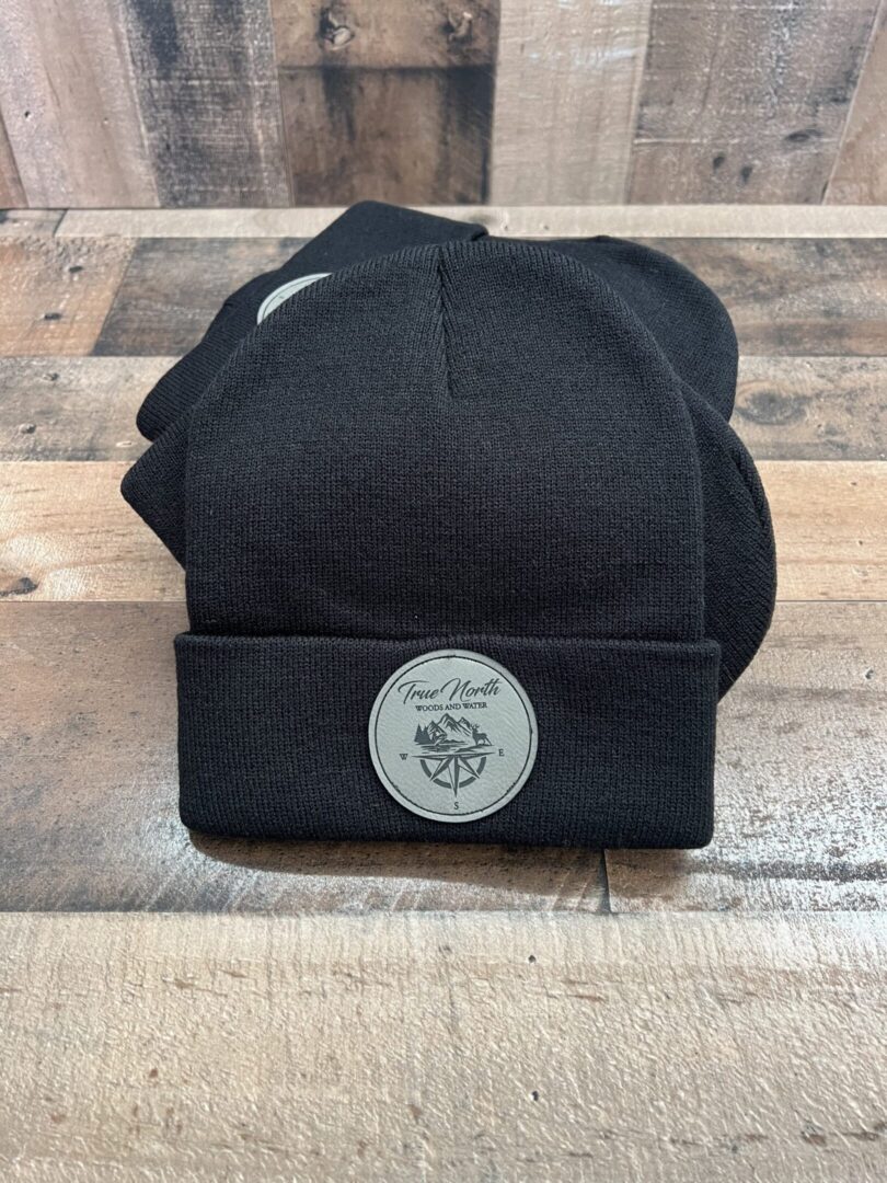 Black beanie hat with a round logo patch on the front.
