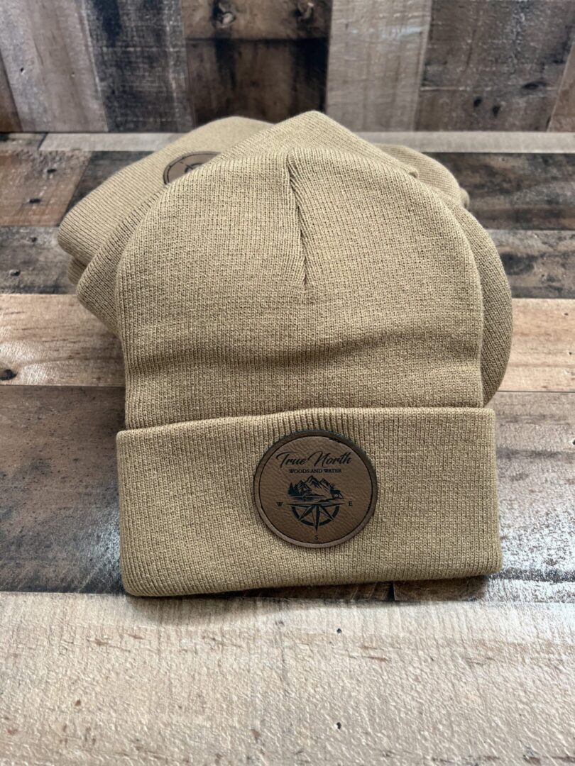 Beige knit beanie with a Marine Corps emblem on a wooden surface.
